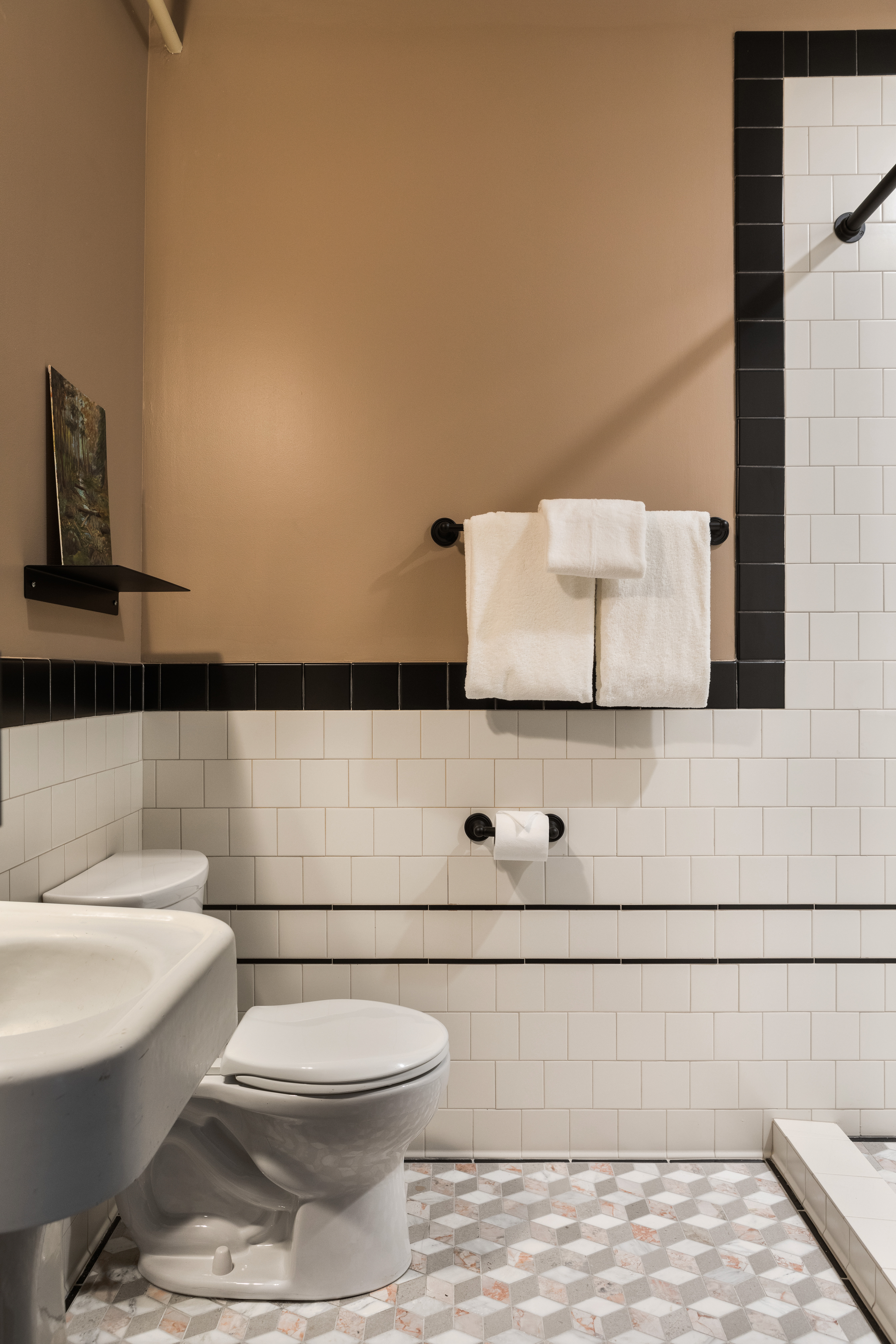 Hotel bathroom with mauve walls, white subway tiles, and a marble floor mosaic