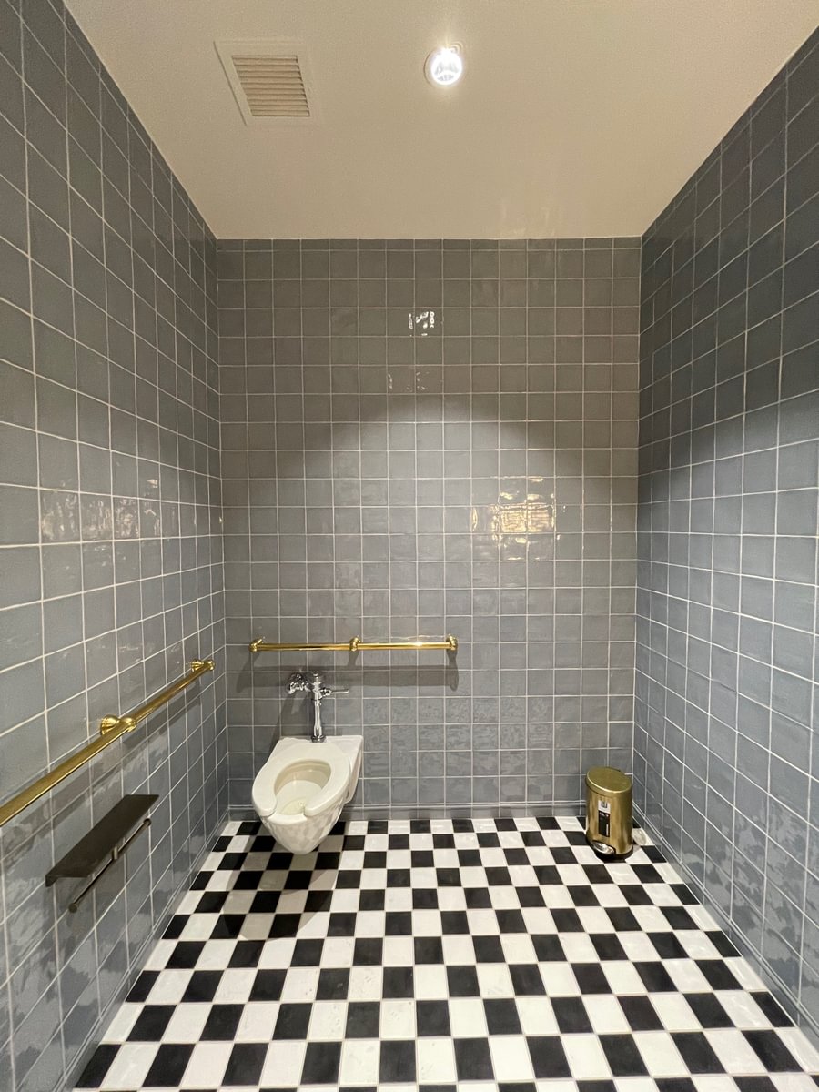 Accessible restroom featuring glossy blue-gray Cev Provencial ceramic wall tile and black-and-white checkerboard flooring at Bond Collective Los Angeles.